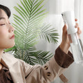 Woman misting her face with the Fine Mist Continuous Setting Spray Bottle