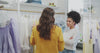 Two women browsing garments on clothing racks in a bright Northline boutique